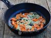 Pink salmon with onions and carrots in a frying pan